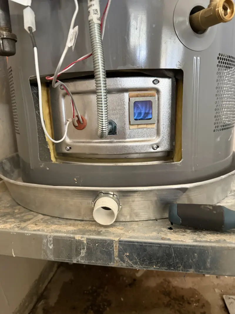 Gas water heater sight glass showing a clean blue burner flame, the sign of complete combustion